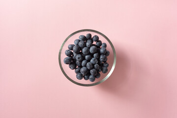 High angle view of blueberries in glass bowl on pink background