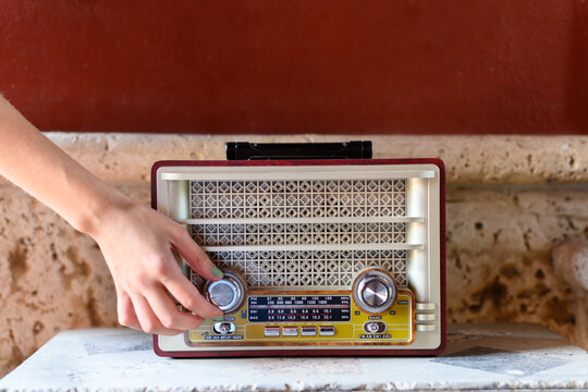 Woman's hand turns on an antique radio