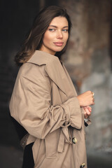 Autumn portrait of a young pretty girl in a coat. A girl in a trendy trench coat walks in the old town