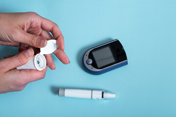 woman getting ready measures blood sugar using a glucometer. diabetes concept on blue background