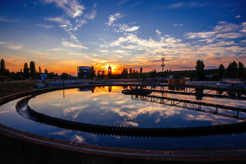 Modern sewage treatment plant. Round wastewater purification tank at sunset - obrazy, fototapety, plakaty