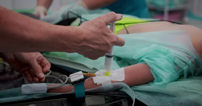 The nurse makes an intravenous infusion, preparing for the operation. Close-up of a hand with a catheter. Pediatric surgery. 