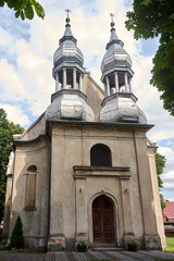Fototapeta na wymiar The facade of the historic baroque church with tin belfries in Stary Dworek
