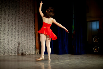 Dancer on stage from the back. Girl in a red dress, white tights and Czechs. Performance of the actress