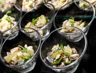 A light snack of potatoes, mushrooms, chicken meat and herbs in transparent serving cups.