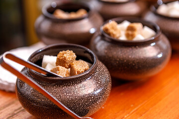 A sugar bowl with tongs filled with fruit sugar is on the table.