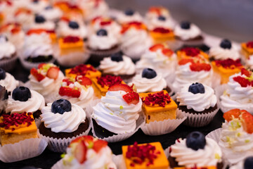 Mini cake selection. Orange cheese cake. Pavlova with strawberry. Chocolate muffin with mascarpone. Delicious professional looking food and snacks served at catering event or party buffet style.