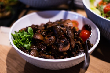 Bowl of smoked and marinated mushrooms. Delicious professional looking food and snacks served at catering event or party buffet style.