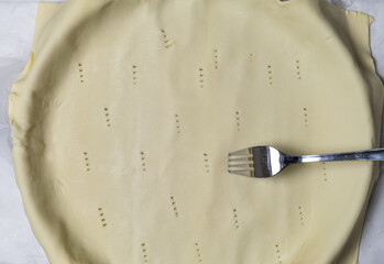raw puff pastry dough in round form with fork