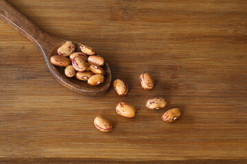 White Beans in a wooden spoon close-up on a wooden background. Vegetarian food.