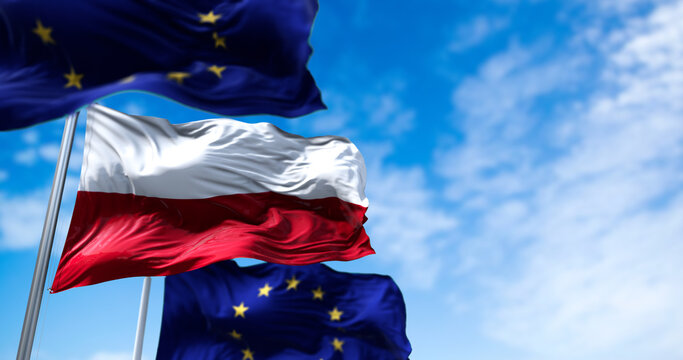 The flags of Poland and the European Union waving in the wind with clear sky in the background