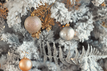 Fototapeta na wymiar Close up photo of toy balls in silver and gold on trendy luxury snowy Christmas tree