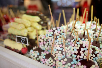 Apples dip in chocolate icing and small marshmallows sold on Christmas market. Candies, sweets and desserts on Xmas time.