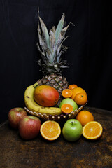 Wooden bowl with fruits, pineapple, apple, orange, mango and banana