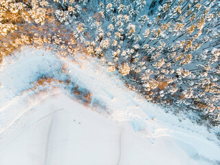 Beautiful aerial view of snow covered pine forests aroung Gela lake. Rime ice and hoar frost covering trees. Winter landscape near Vilnius, Lithuania.
