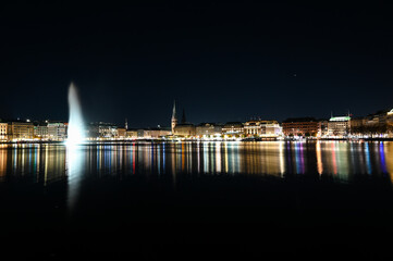 City of Hamburg at night. Panoramic view of Hamburg and Aussen-Alster lake, Germany. Buildings, towers and Alsterfontäne. 