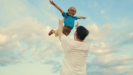 Kid Plays With Daddy. Dad throws his happy son into blue sky, child is pilot, dreams of flying....