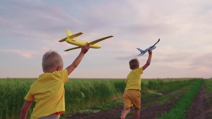 Boys, children run through wheat field play with toy airplane in hand, dream of flying. Child plays...