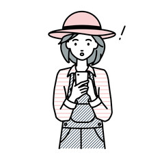 立ってスマートフォンを操作して何かに気づいて驚いた農家の女性
