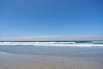 Fototapeta na wymiar sand beach with soft waves. White foam on a clean sandy shore.