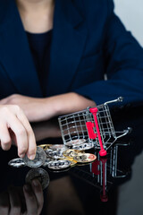 Fototapeta na wymiar Woman holding some pieces of golden Bitcoin token in shopping cart