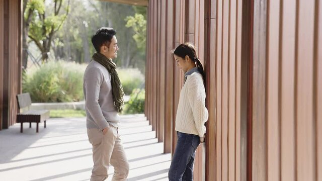 young asian couple conversing outdoors in city park