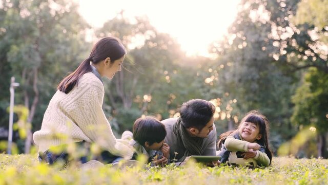 young asian family with two children relaxing outdoors in city park