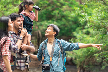 A group of young Asians are planning and looking at maps for camping in the forest.Asian and caucasian are backpackers.Tourism, adventure and summer vacation concept