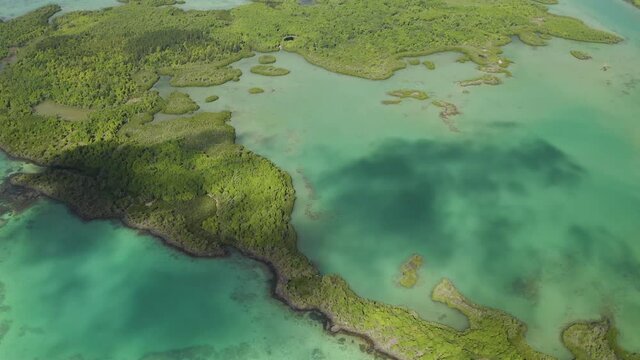 Aerial : Flying with clouds shadows over turquoise lagoon Amber island Mauritius