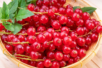 Table top view bunch of red currant in wooden plate, Red currant berries with leaf on a  wooden table.