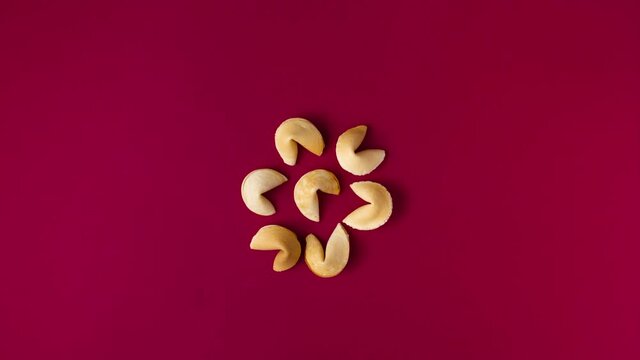 a stopmotion of a box full of fortune telling cookies opening, cookies dancing, form a line and crack one after another