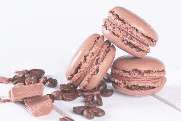Macaroons with Sweet Chocolate and Coffee Beans on White Wooden Table