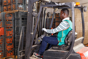 Fototapeta na wymiar Portrait of African American man using forklift for stacking boxes with mandarins at a warehouse