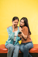 a girl cries sadly looking mobile phone while leaning on her friend's shoulder