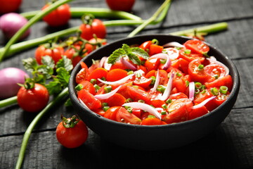 Bowl of tasty fresh tomato salad on a rustic kitchen table.