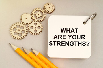 On the table are gears, pencils and a notebook with the inscription - What Are Your Strengths