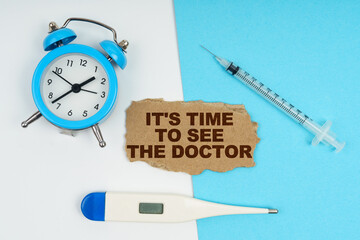 A clock, a thermometer, a syringe and a cardboard with the inscription - It is time to see the...