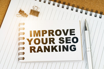 On the table there is a pen, clamps and a notebook with the inscription - IMPROVE YOUR SEO RANKING