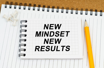 There are two notebooks and a pencil on the table. On the top notepad, the inscription - New Mindset New Results