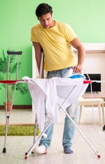 Leg injured man doing clothing ironing at home