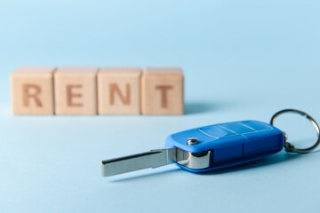 Car key with word RENT on blue background, closeup