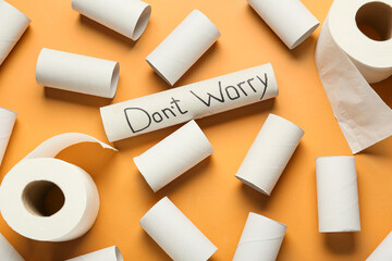 Rolls of toilet paper and cardboard tubes with text DON'T WORRY on color background
