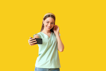Pretty young woman taking selfie on color background