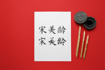 Tools for calligraphy and paper with Asian hieroglyphs on color background