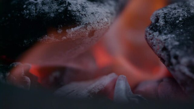 Extreme close up of a charcoal briquette ontop of a chimney starter surrouynded by flames and glow