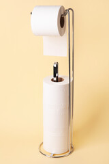 Modern holder with toilet paper rolls on beige background