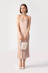 Beautiful woman with stylish jewelry carrying handbag on white background