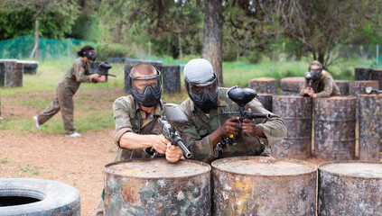 Two men in camouflage and masks holding guns ready for playing paintball with friends