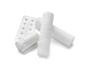Pills and medical gauze rolls on white background