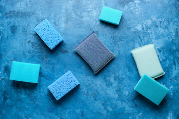Blue cleaning sponges on color background